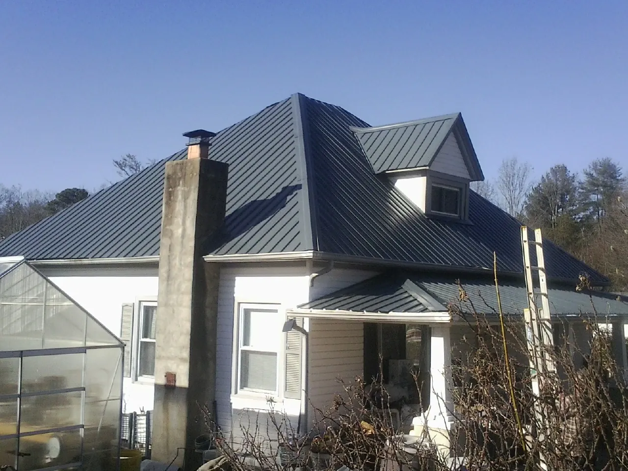 Dark blue standing seam metal roof on a white farmhouse with dormer — Slate & Tile Roof Repair by Roofing Brothers in Granite City