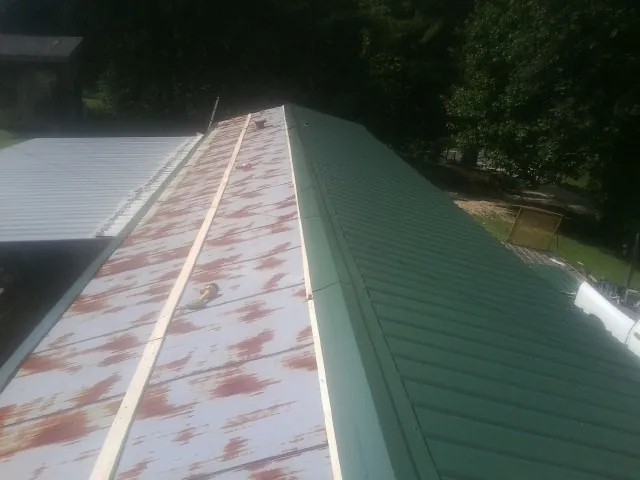 Old rusted panels beside newly installed green metal roofing — Wind Damage Roof Repair by Roofing Brothers in Granite City