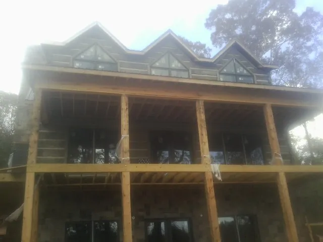 Dormers and porch framing on a large log home under construction — Roof Coating work by our crew in Granite City