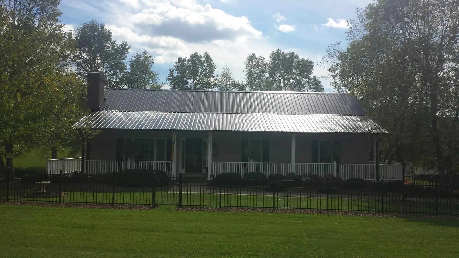 Gray metal roof on a brick ranch with a full width front porch — Gutter Guard Installation work by our crew in Granite City
