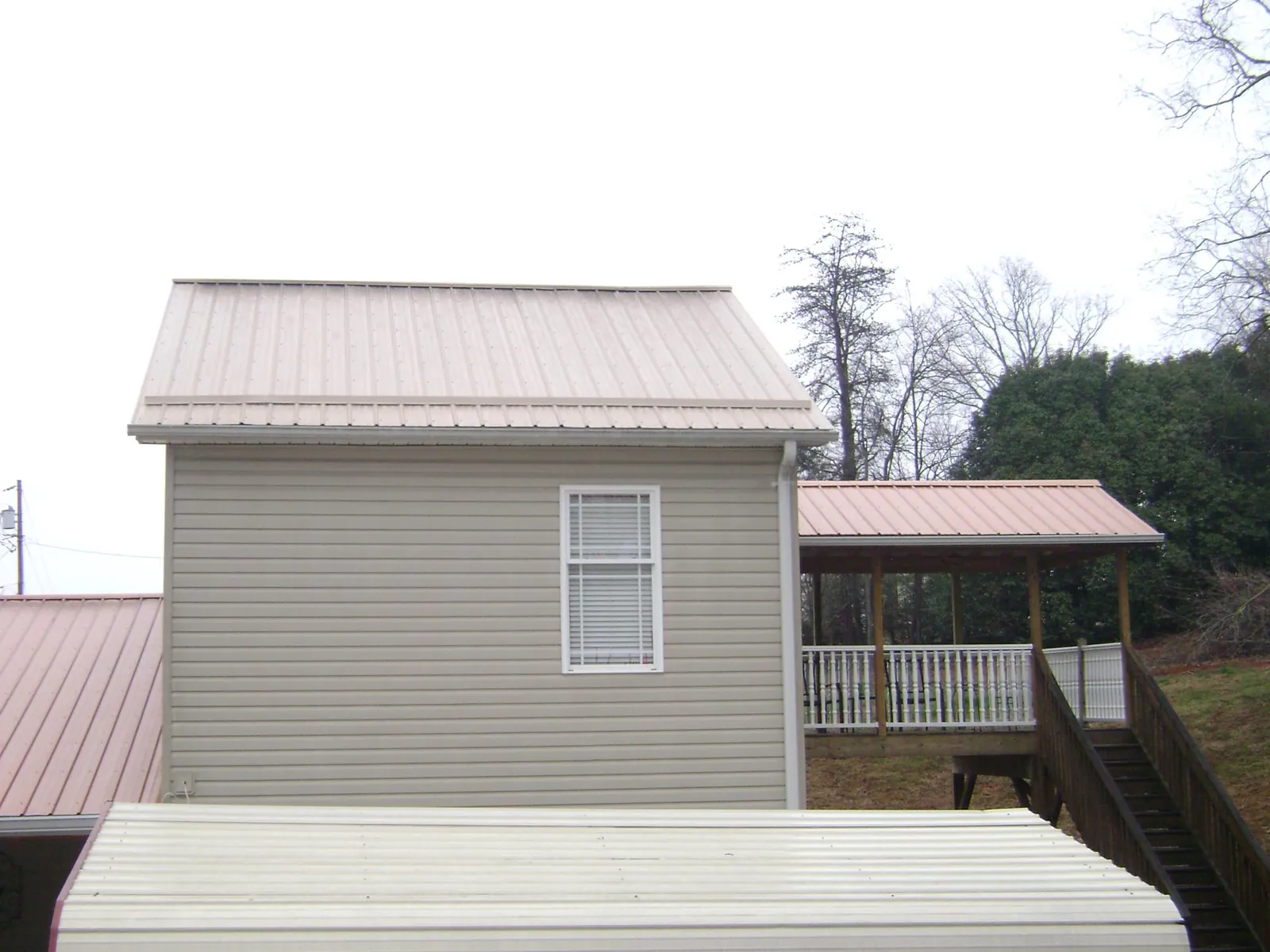 Tan metal roofs on a two story addition and attached porch, from a Roof Replacement job in Granite City