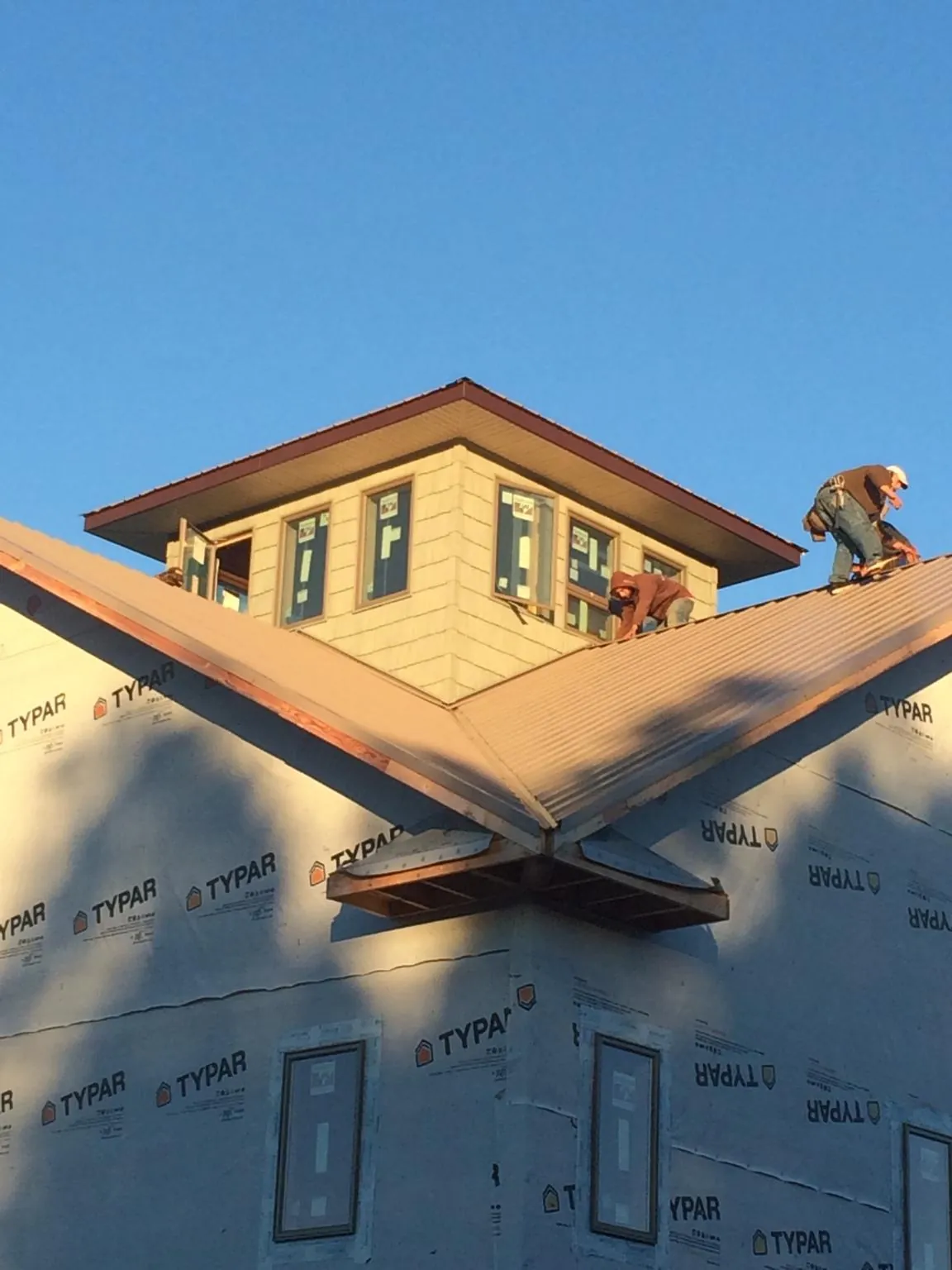 Roofers working around a rooftop cupola on a new metal roof at sunset — Roof Waterproofing in Granite City by Roofing Brothers